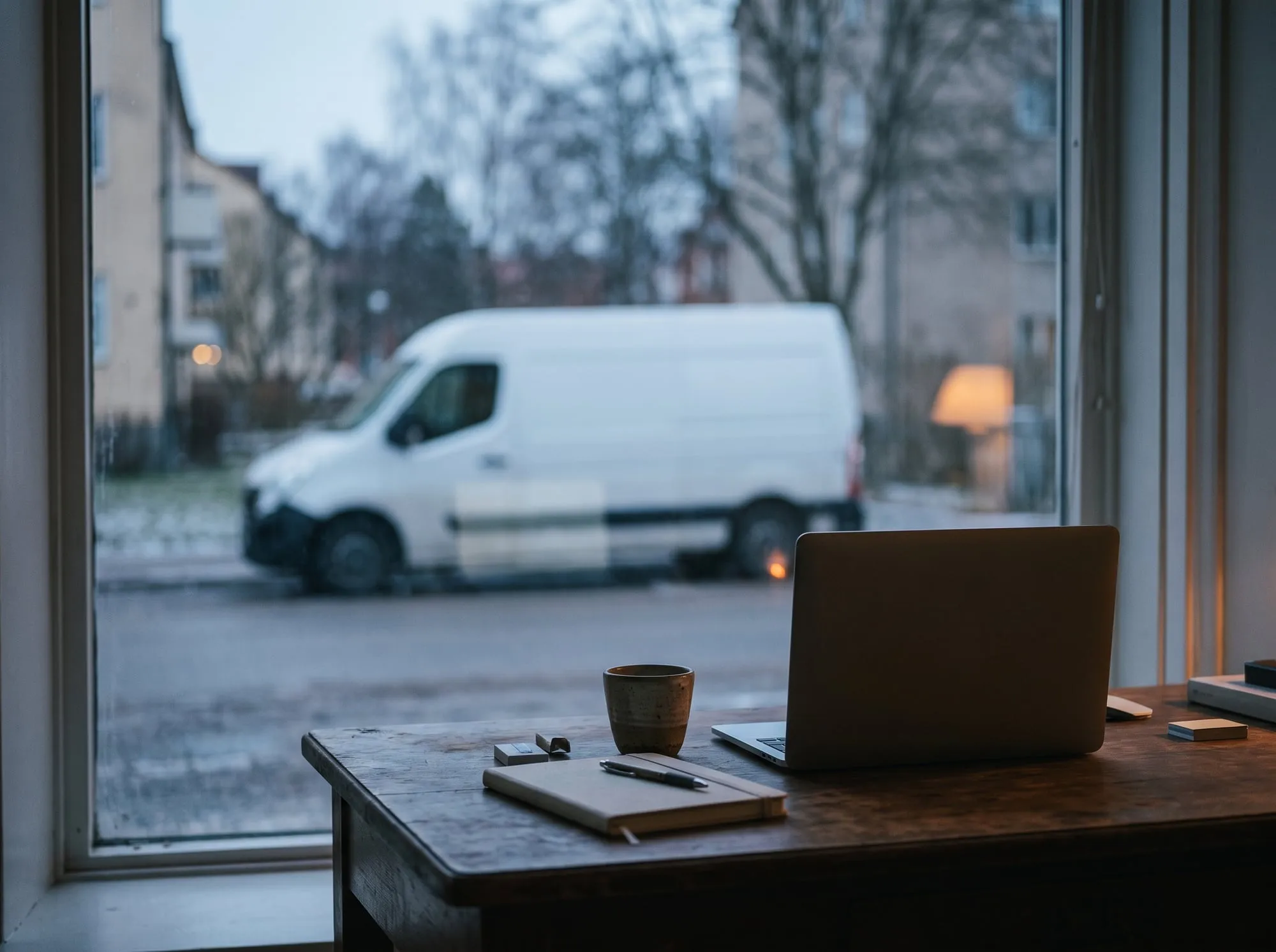 A desk by the window, a white van parked outside