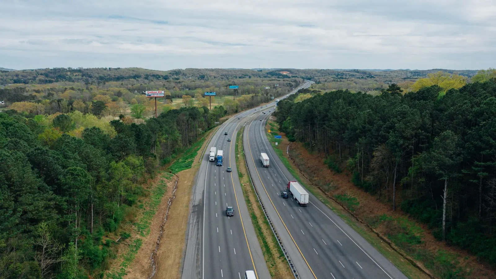 Aerial view of a motorway through forest with trucks running in both directions