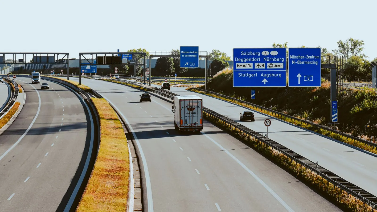 Lorries and cars on a German autobahn seen from an overhead bridge, with motorway signs to Salzburg, Nürnberg and Stuttgart