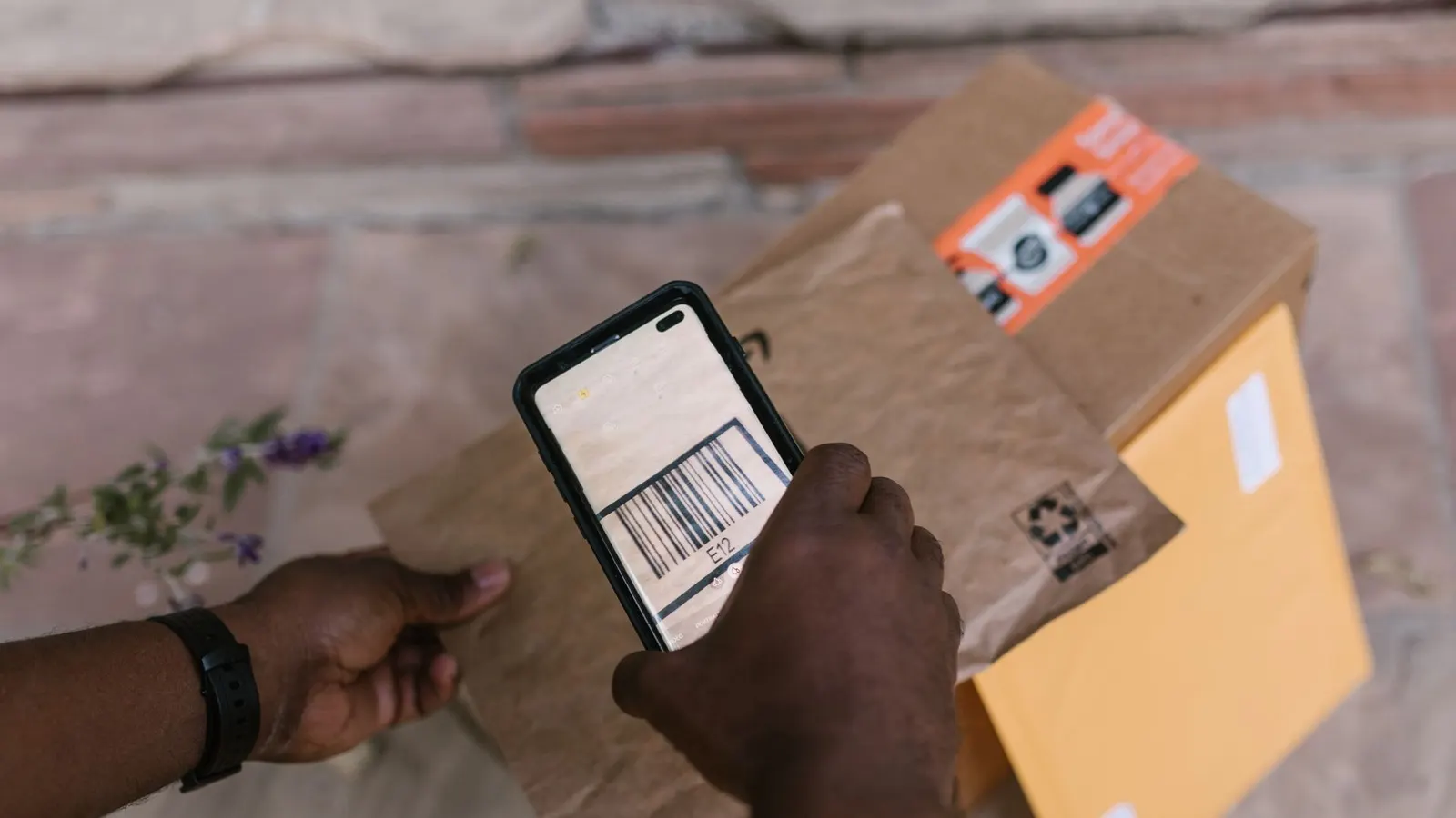 A courier scanning a parcel barcode with a smartphone at handover