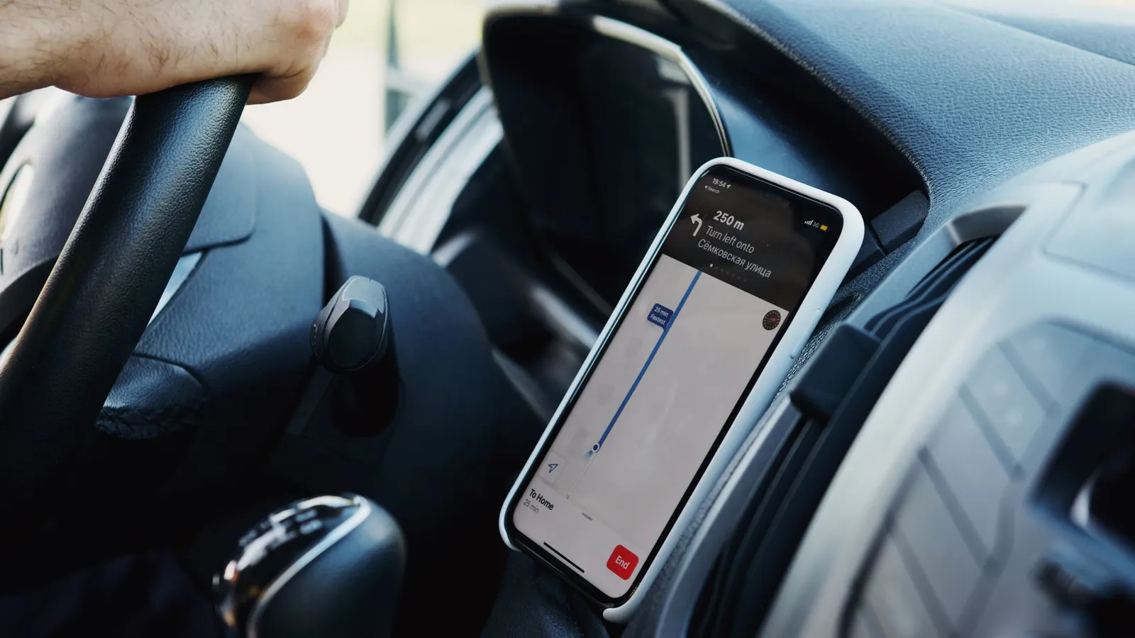 A smartphone in a dashboard mount showing turn-by-turn navigation