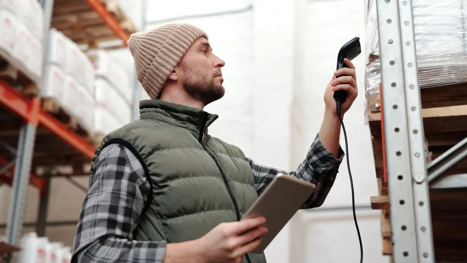 A warehouse worker scanning racking with a barcode scanner and a tablet