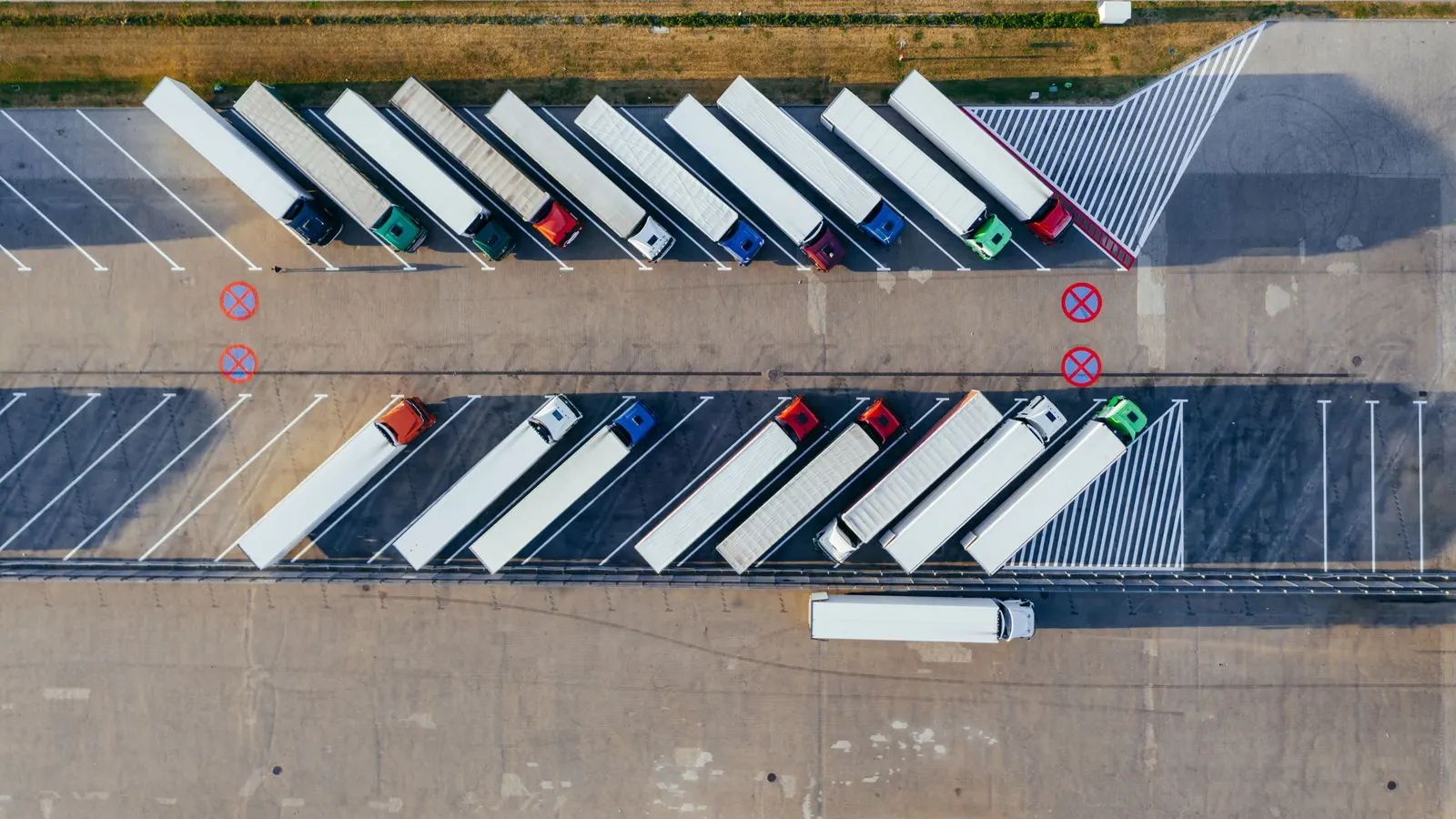 Aerial view of articulated lorries and their trailers parked in rows at a truck park