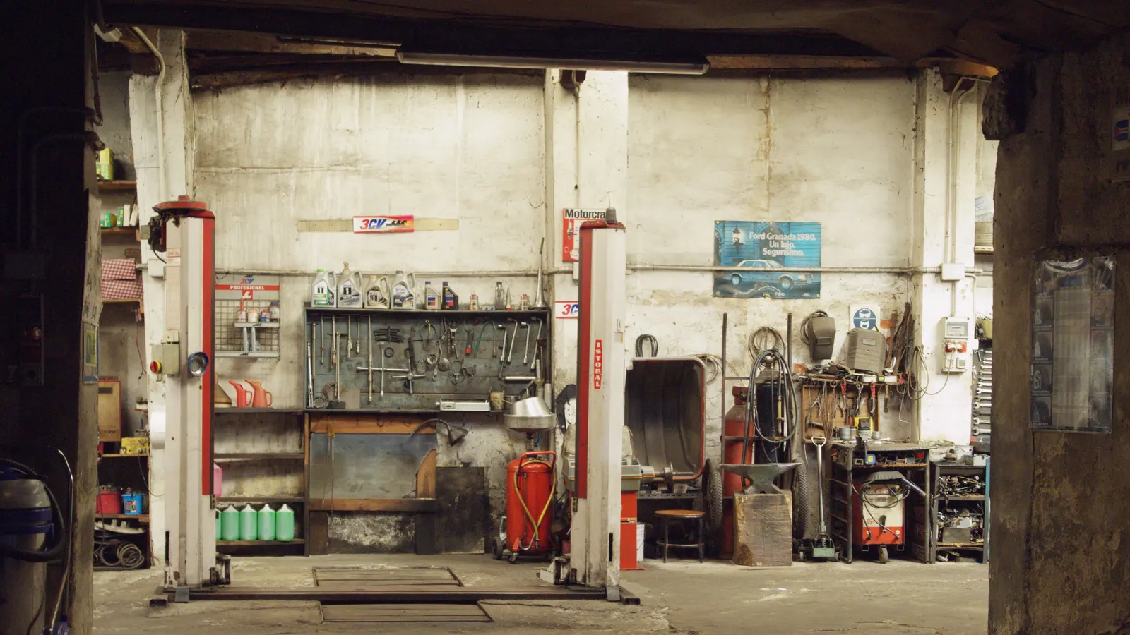An empty workshop bay with vehicle lifts, hand tools and machinery along the walls